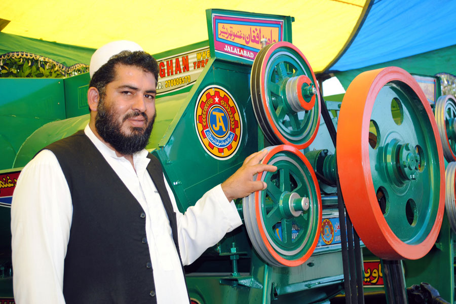 Photo of a farmer in Afghanistan standing next to farm machinery.