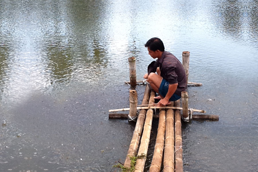Photo of a man tending to a fish farm.