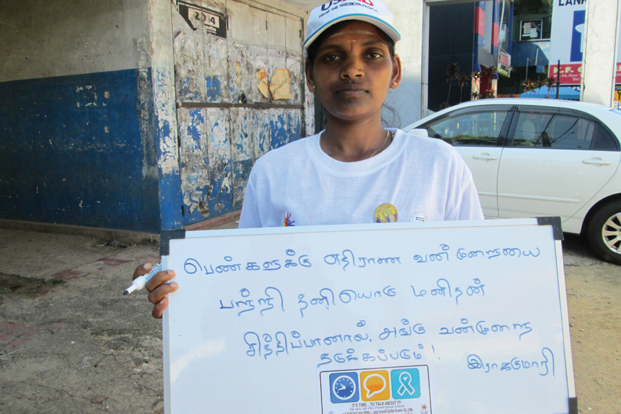 Photo of a Tamil woman holding a sign.
